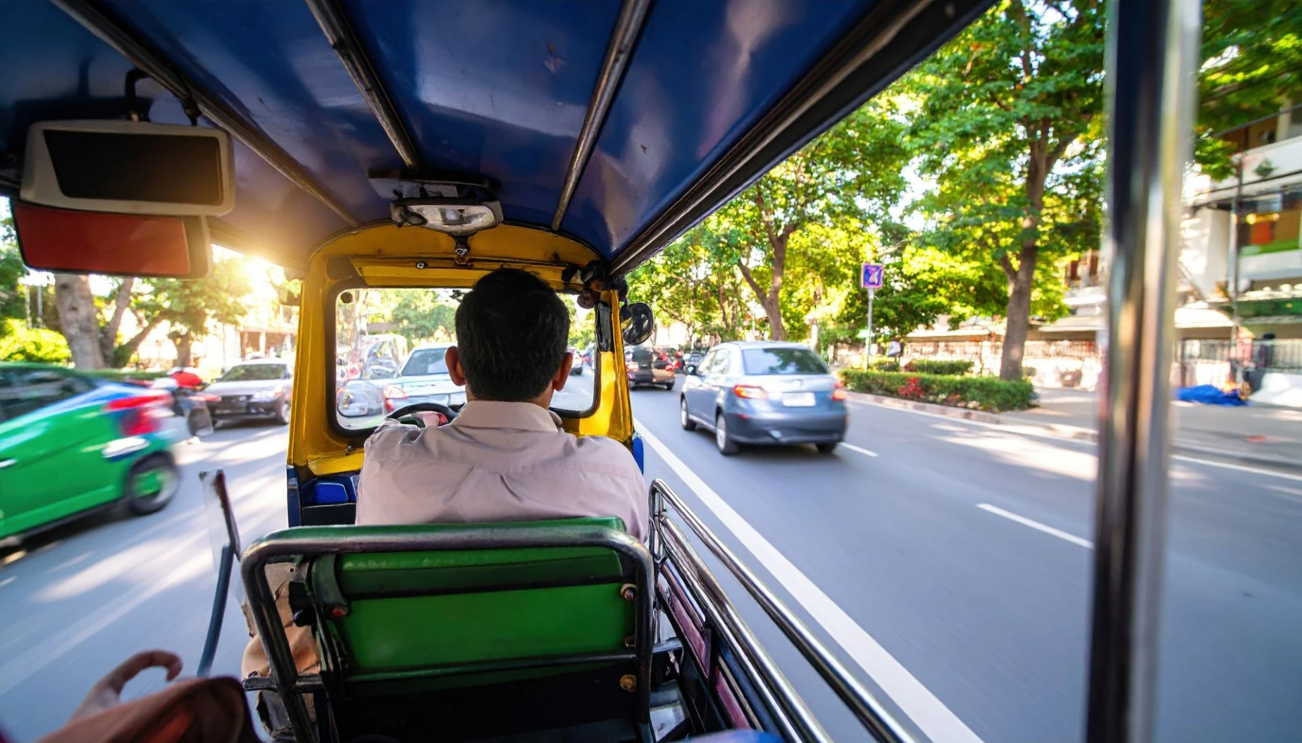 A man driving a tuk tuk on a busy street